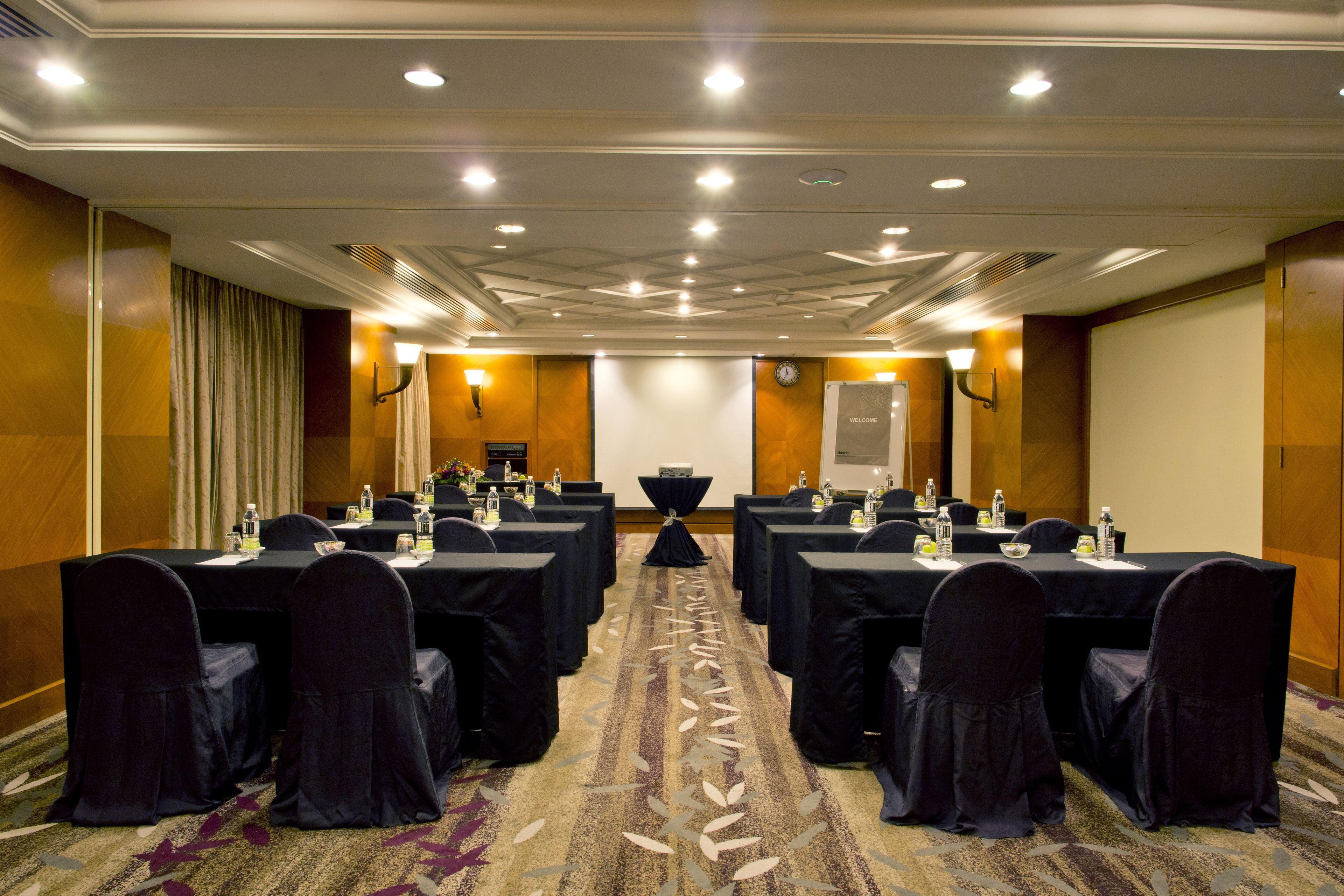 A conference room with multiple tables and chairs, equipped with water bottles and nameplates.