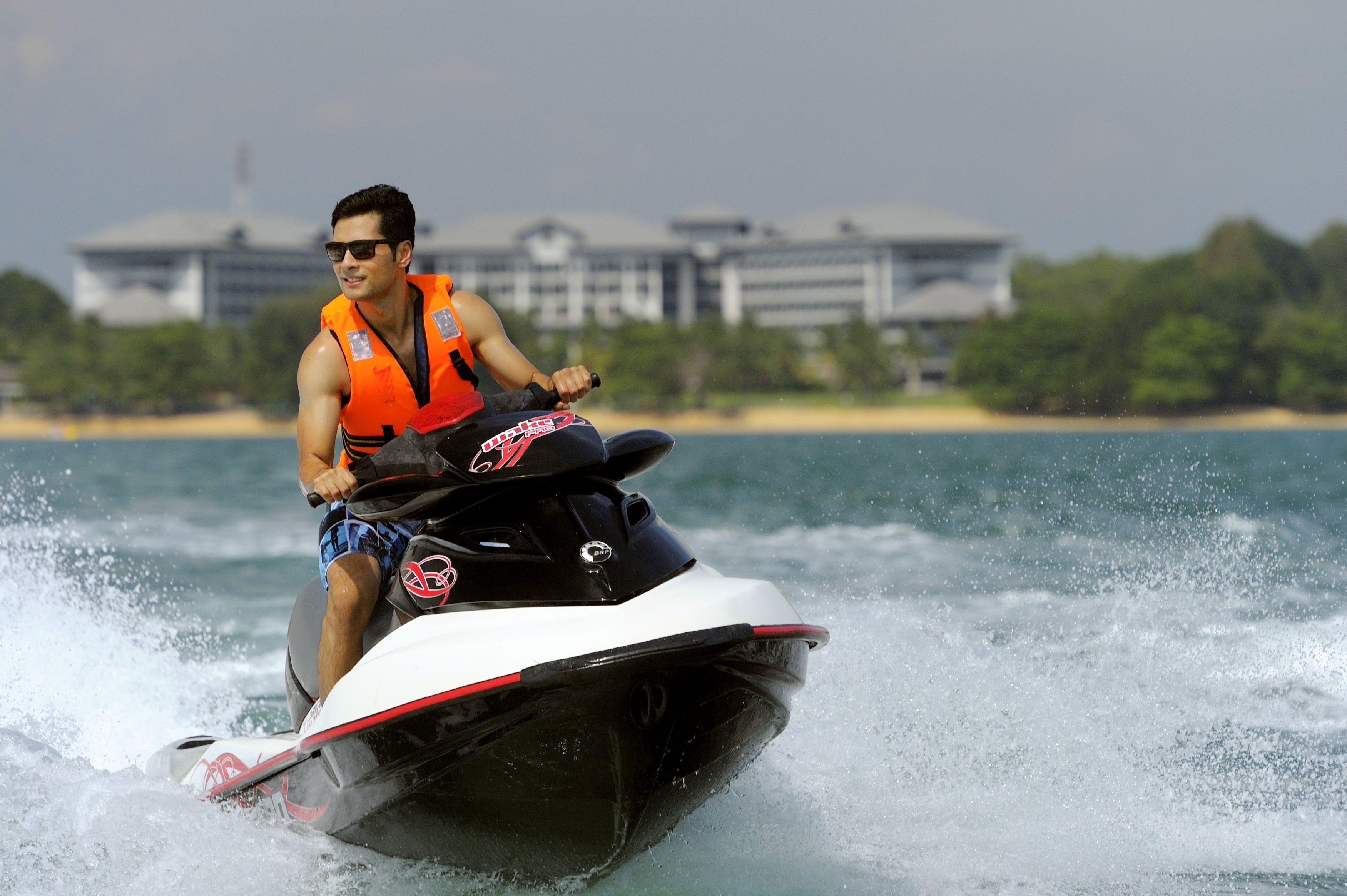 A person jet skiing on a body of water with a building in the background.