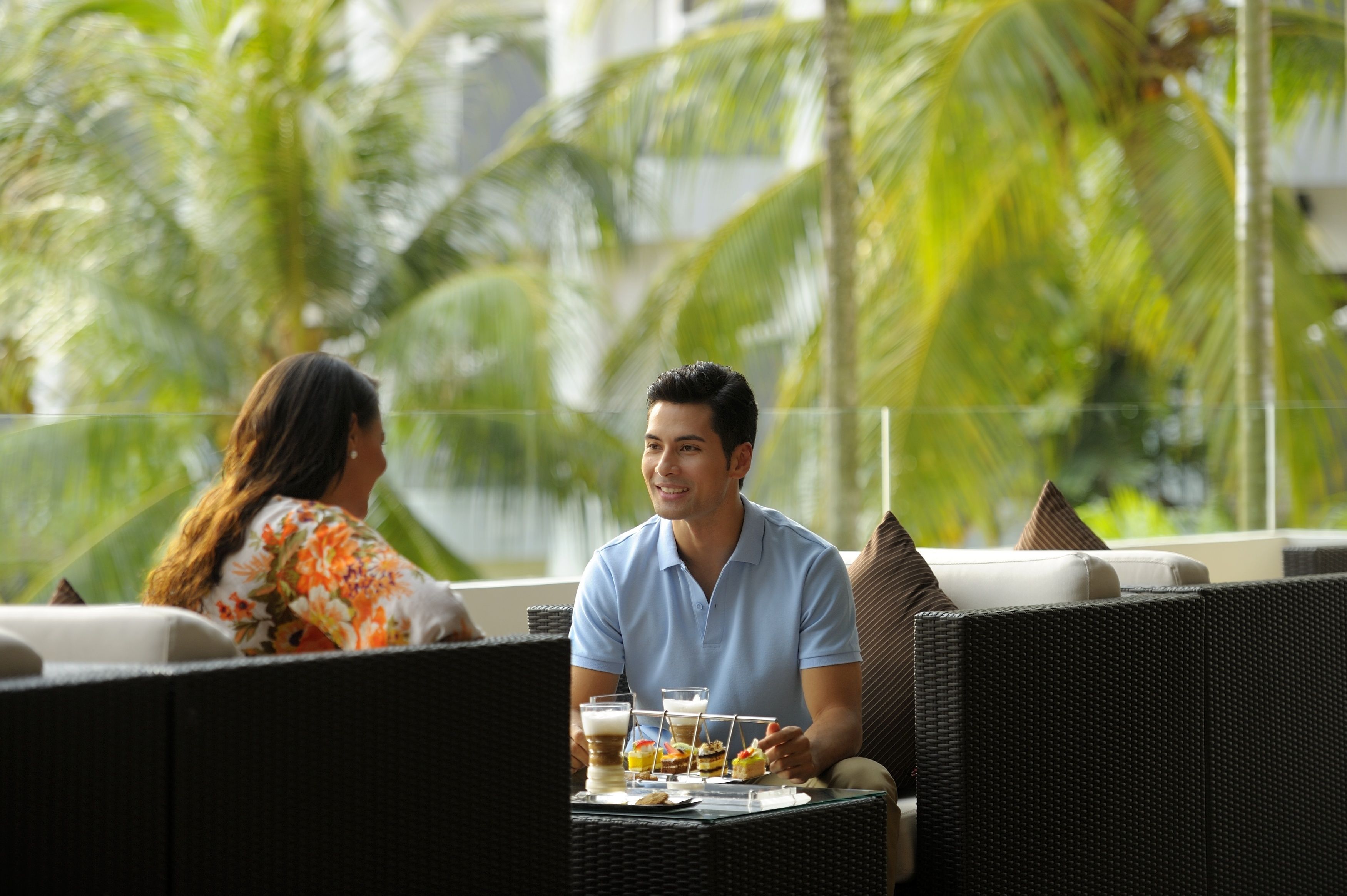 Una pareja cenando en una mesa al aire libre, con vistas a palmeras.