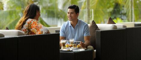 Una pareja cenando en una mesa al aire libre, con vistas a palmeras.