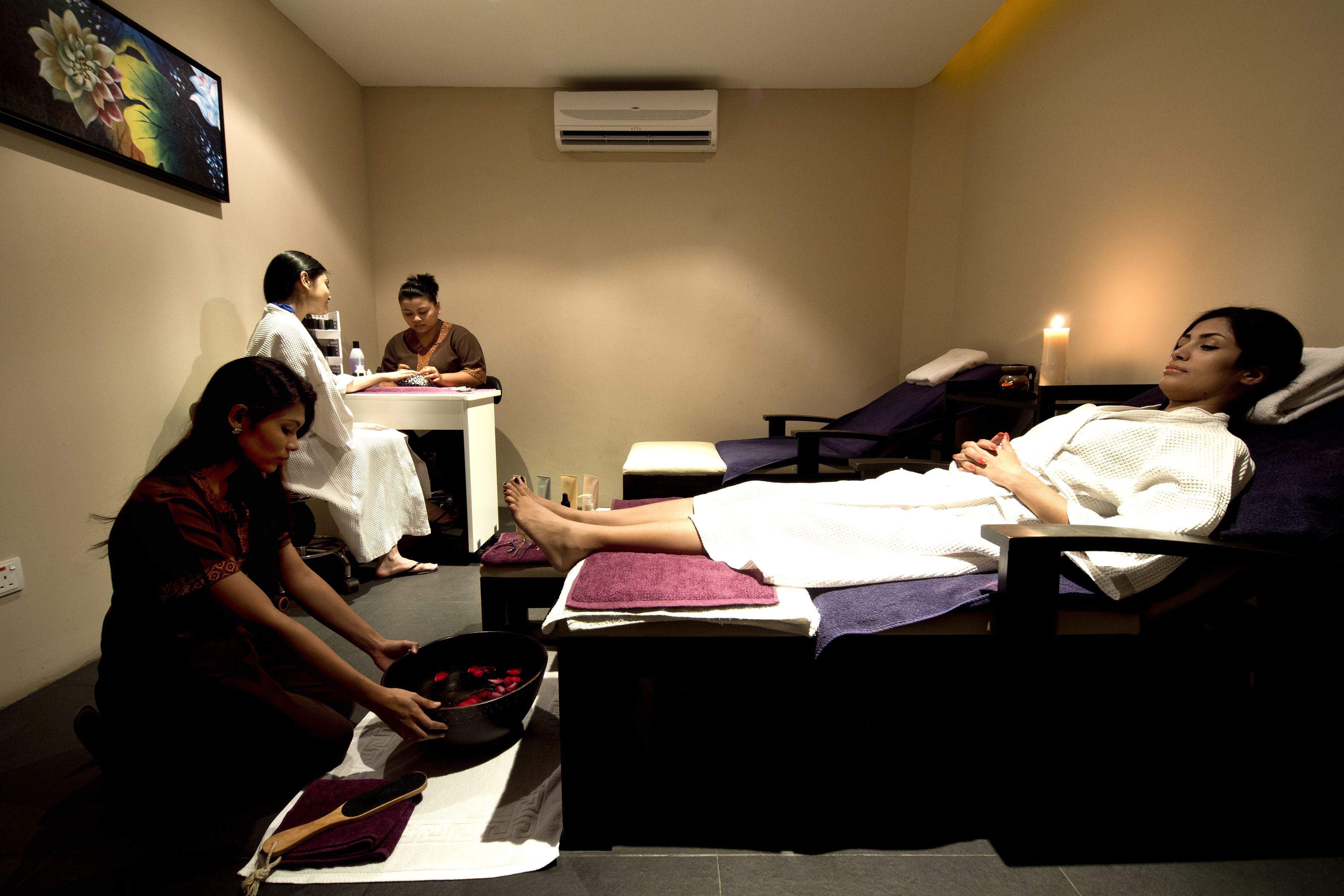 A spa room with a massage table, a foot bath, and a small sink.