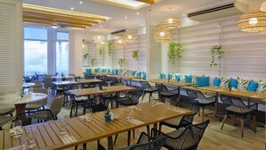 A restaurant with wooden tables, black chairs, and hanging wicker chandeliers. - Be Resorts - Mactan (Lapu-Lapu)