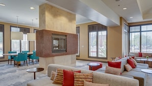 A spacious lobby with a fireplace, seating areas, and large windows. - Hilton Garden Inn Phoenix Airport North (Phoenix)