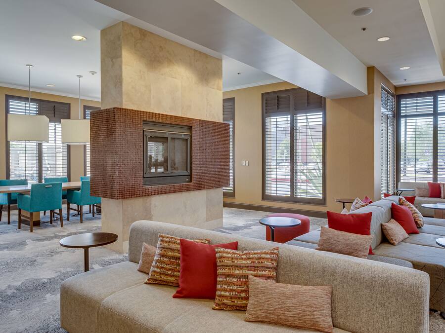 A spacious lobby with a fireplace, seating areas, and large windows.