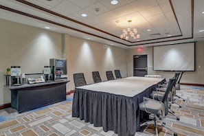 A conference room with a long table, chairs, a projector screen, and a coffee station. - Hilton Garden Inn Phoenix Airport North (Phoenix)