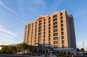 Un hotel alt, de color beix, amb teulada plana i un rètol que diu "Hilton Garden Inn".