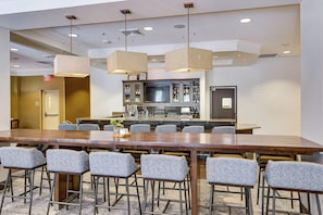 A conference room with a long table, chairs, a bar area with a TV, and a kitchenette. - Hilton Garden Inn Phoenix Airport North (Phoenix)