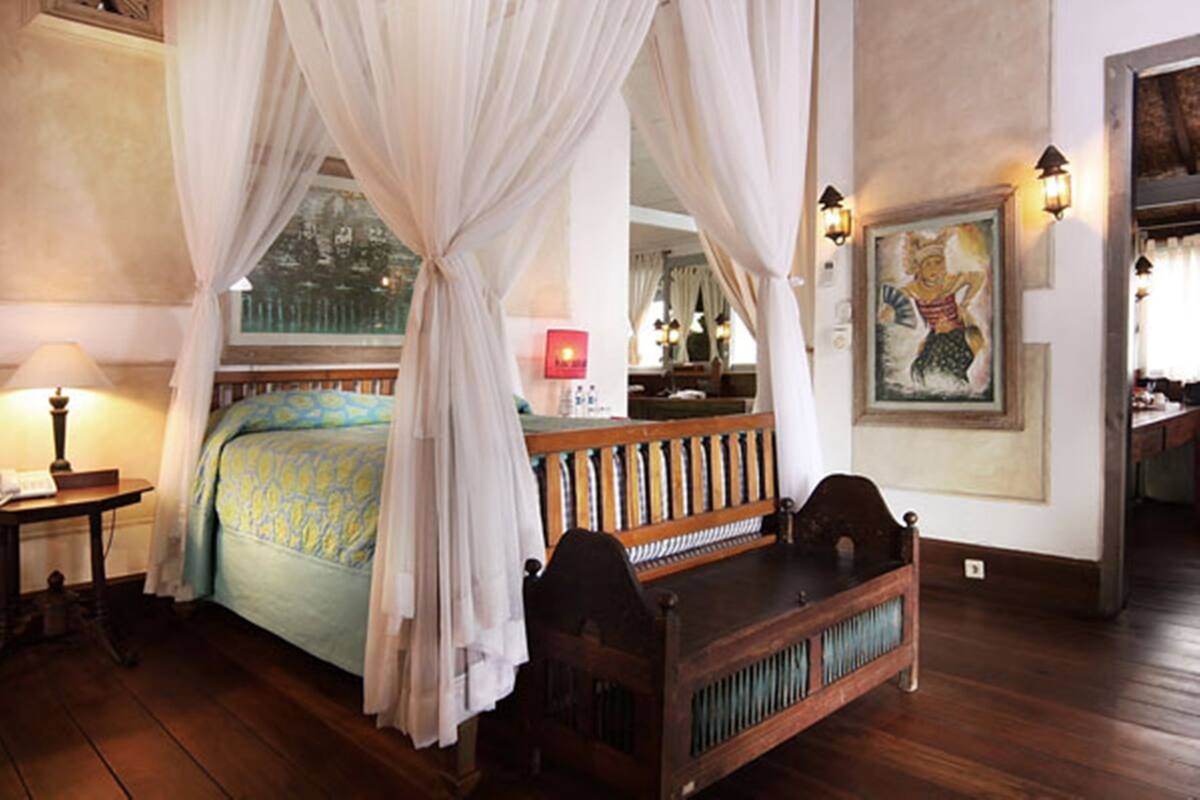 Ein traditionell eingerichtetes Schlafzimmer mit Baldachinbett, Holzmöbeln und einem Gemälde an der Wand.