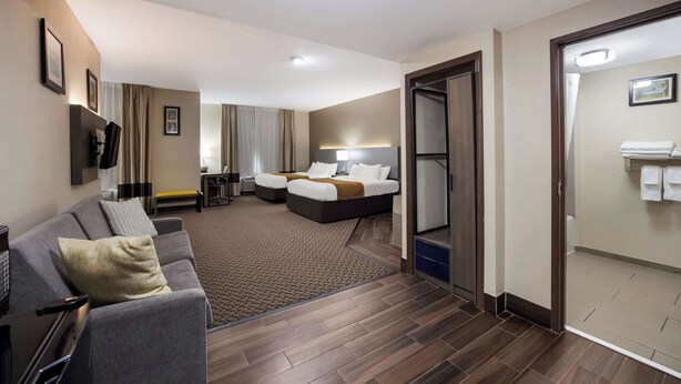 A hotel room with a sofa, a bed, a desk, and a bathroom. - Comfort Inn & Suites Midway - Tallahassee West (Midway)