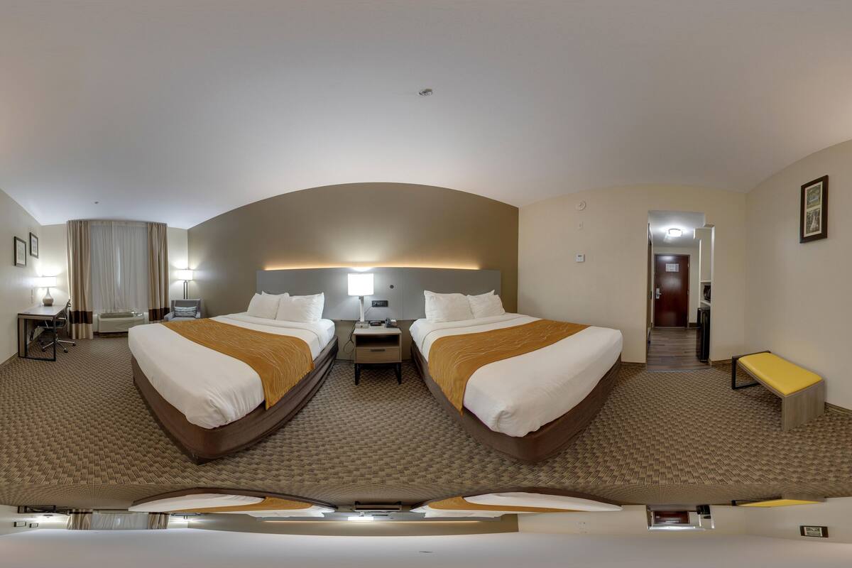 Une chambre d’hôtel avec un grand lit, un bureau, une chaise, une petite table et un téléviseur.
