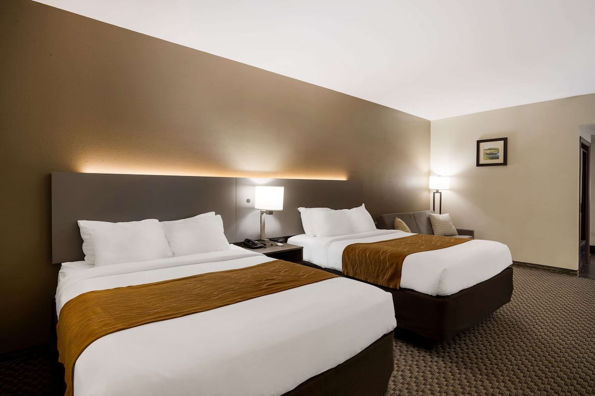 Une chambre d’hôtel avec deux lits, une tête de lit, des lampes de chevet et un sol recouvert de moquette.
