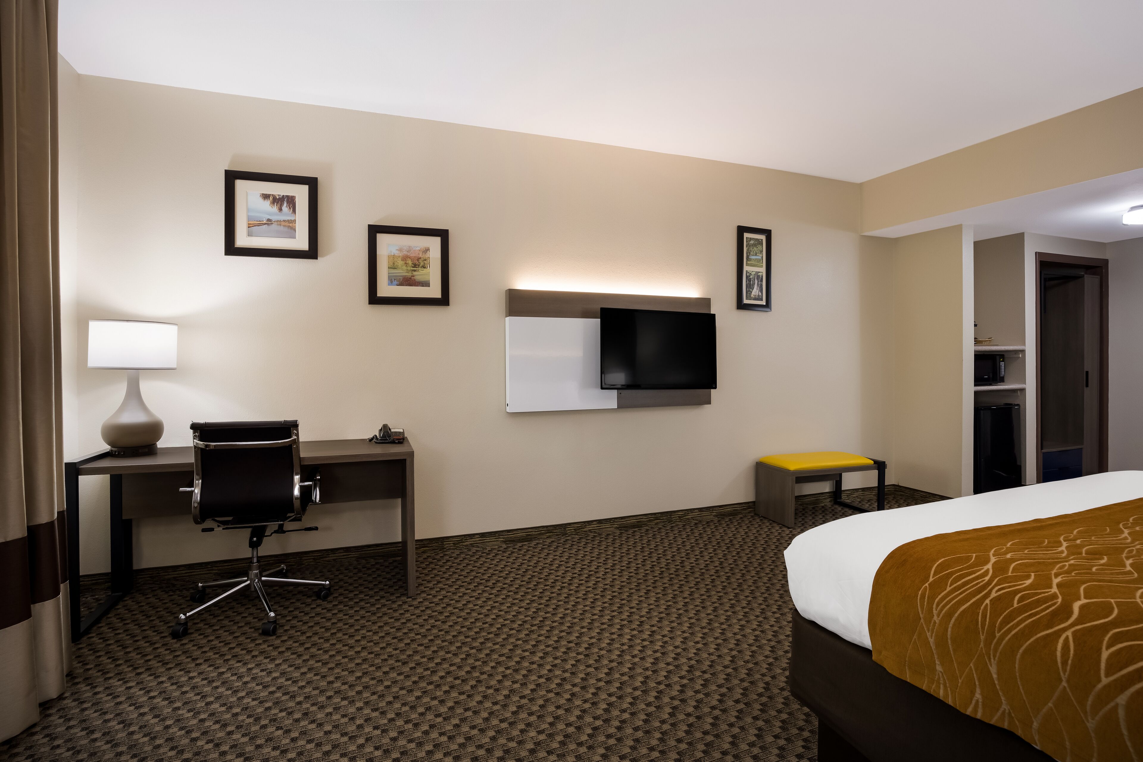 A hotel room with a bed, desk, chair, and a television.