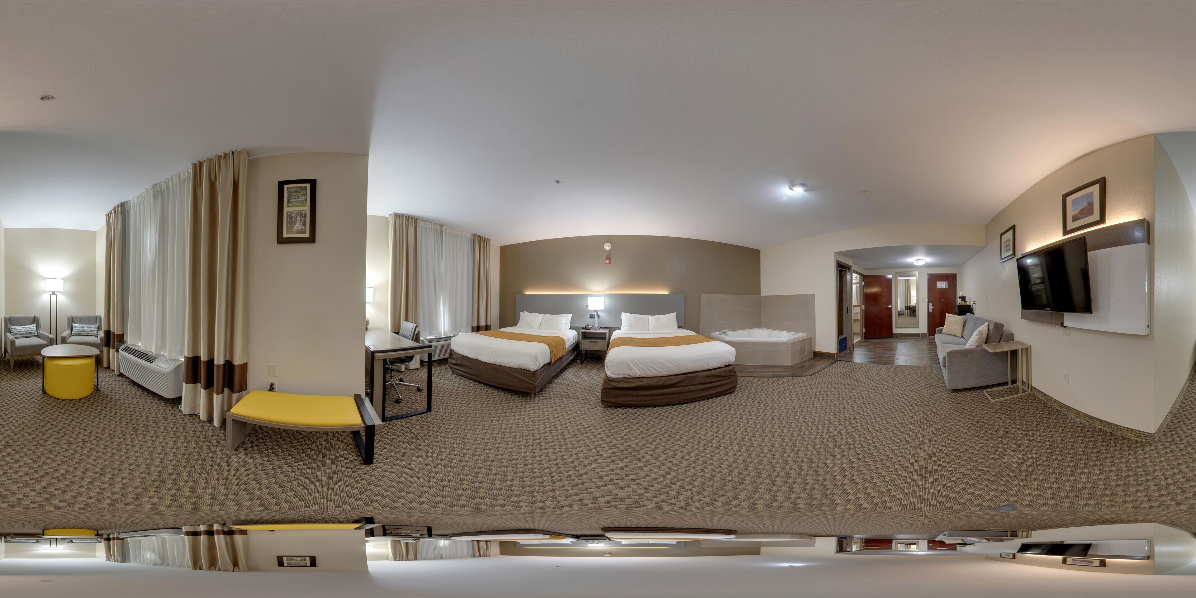 A hotel room with a bed, a desk, a chair, a sofa, a TV, and a bathroom.