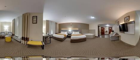 A hotel room with a bed, a desk, a chair, a sofa, a TV, and a bathroom.