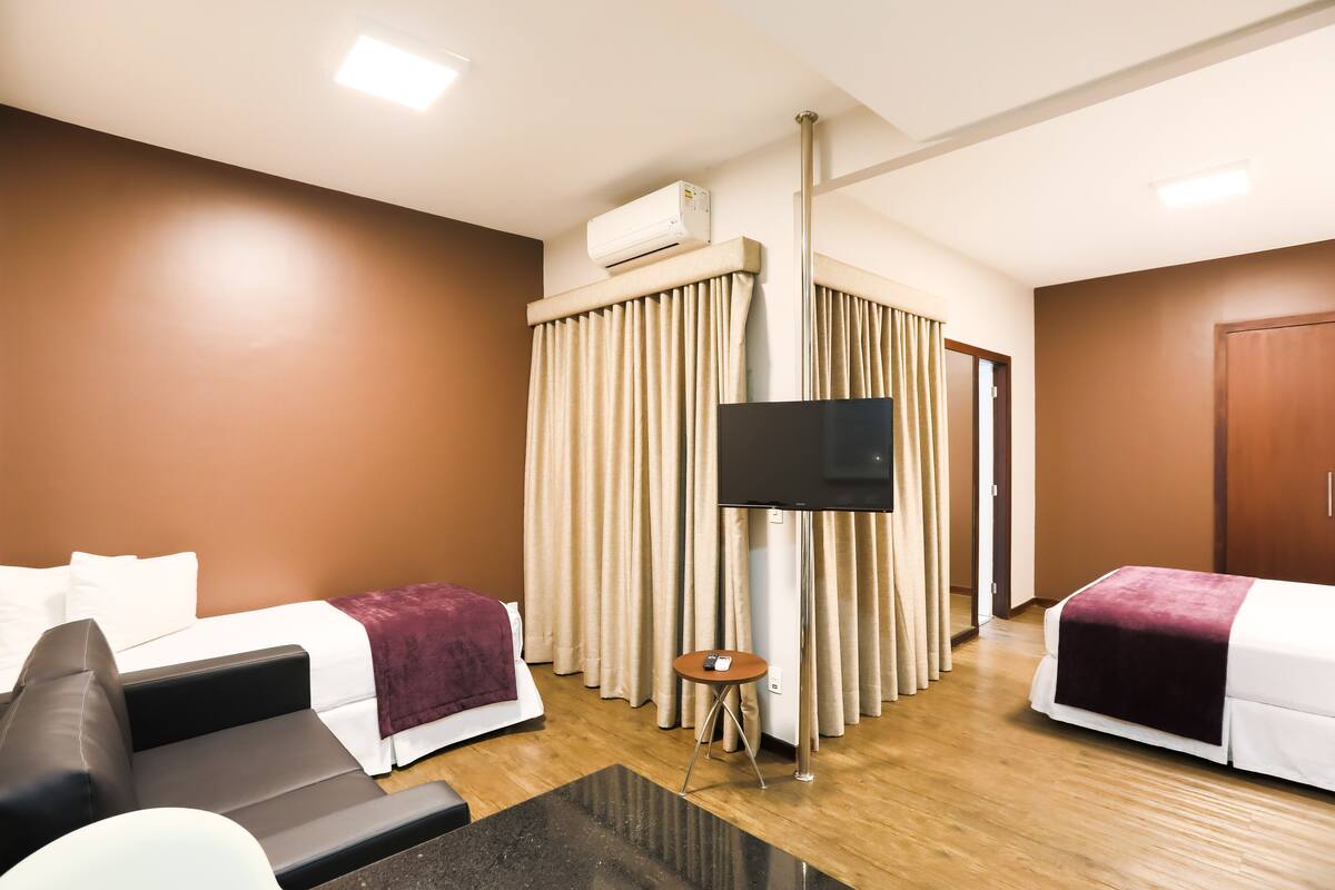 A hotel room with a bed, a sofa, a TV, and a small table.