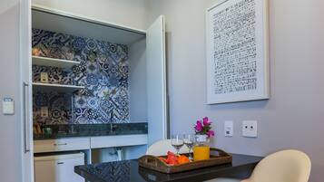 A compact kitchen with a patterned backsplash, a dining table with chairs, and a wall-mounted artwork.