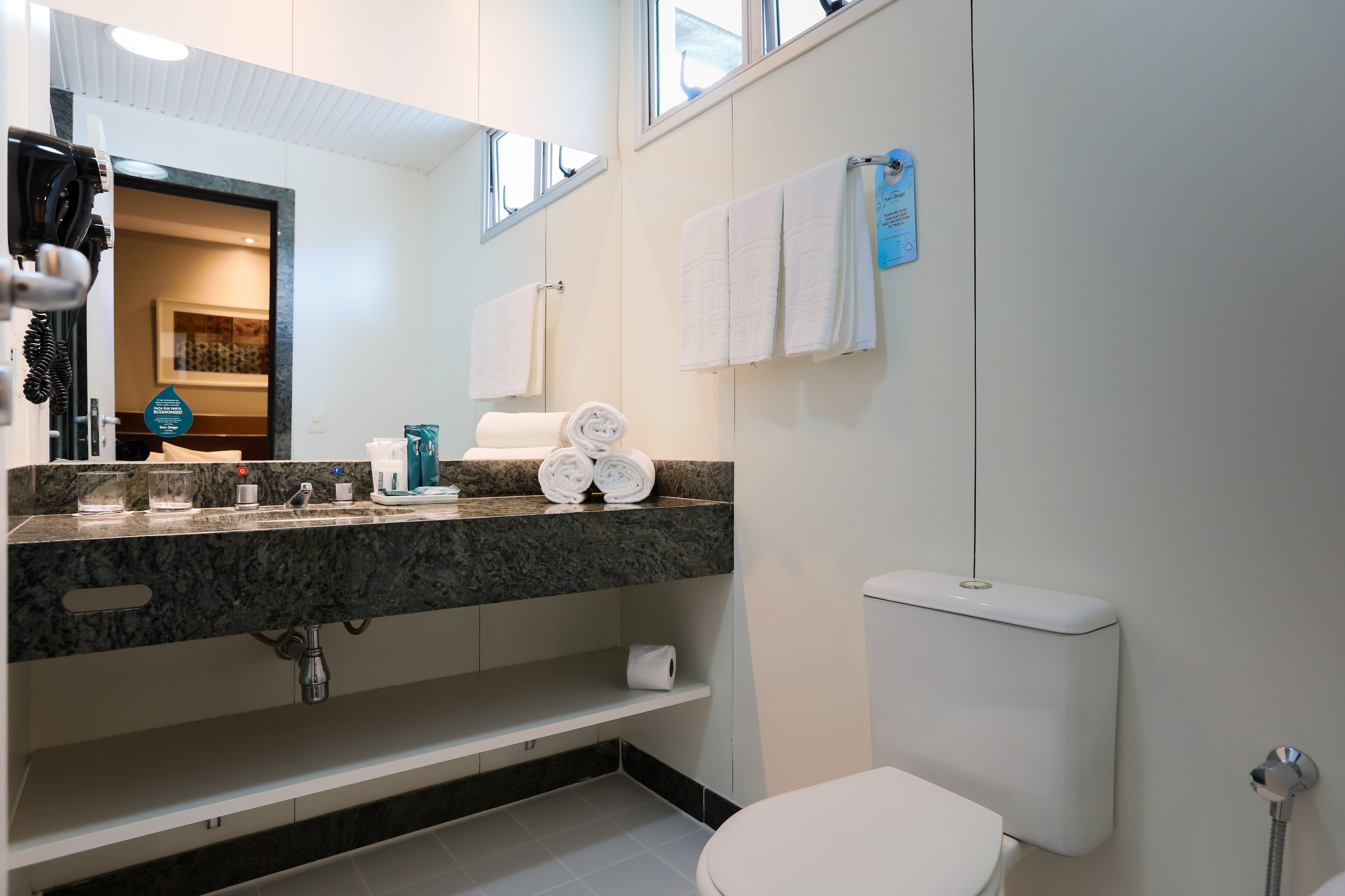 A modern bathroom with a marble countertop, a toilet, and a sink.