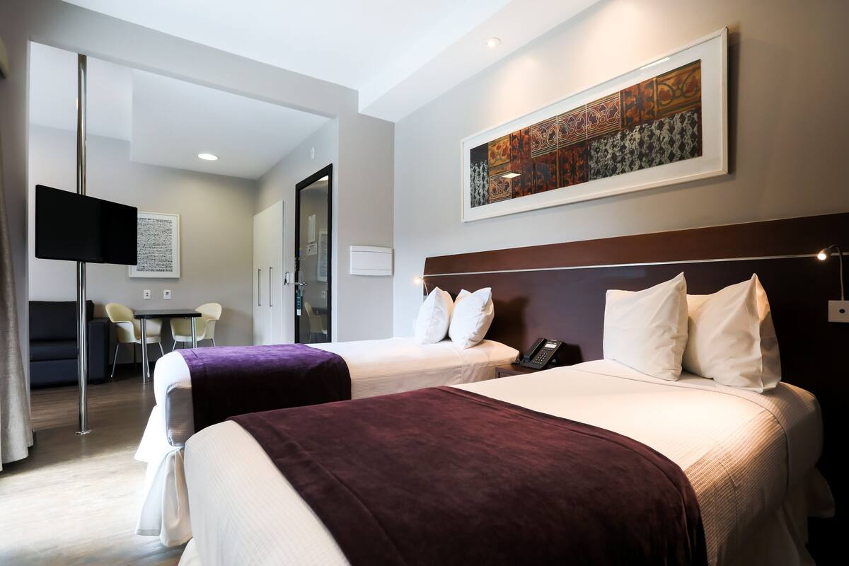 A hotel room with two beds, a desk, and a chair.