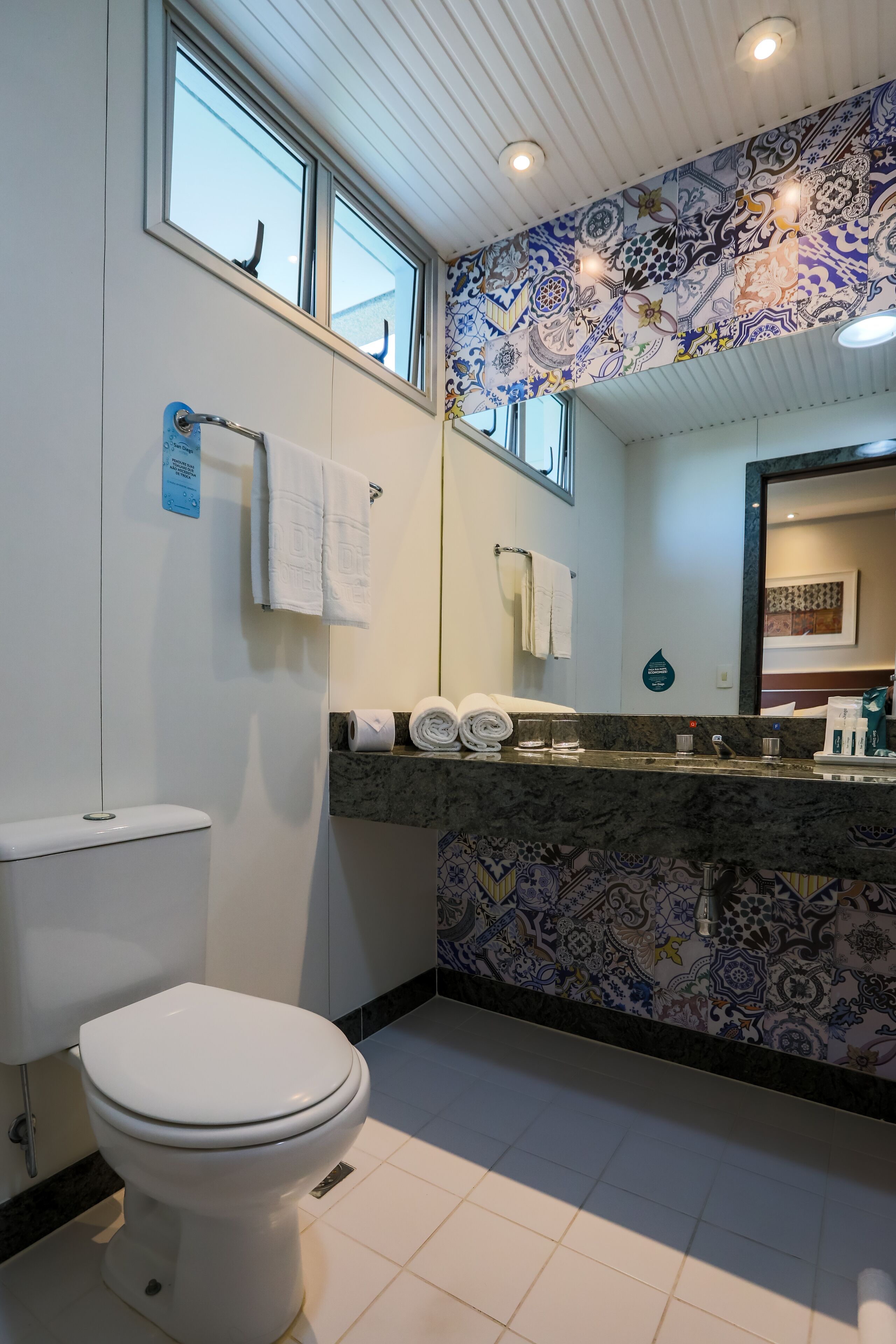 A bathroom with a toilet, a sink with a marble countertop, and a patterned backsplash.