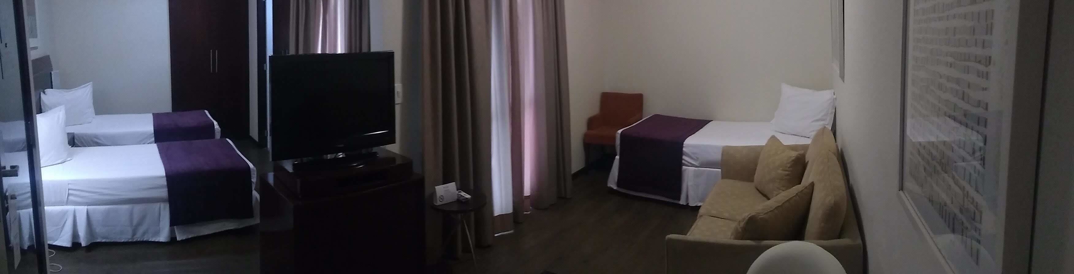 A hotel room with two beds, a TV, a small table, and a chair.