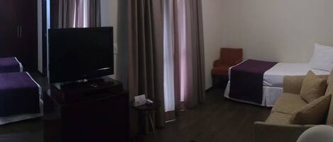 A hotel room with two beds, a TV, a small table, and a chair.
