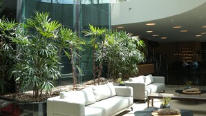 Eine großzügige Lobby mit moderner Glasfassade, einem weißen Sofa und einigen Kübelpflanzen.