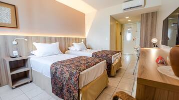 A hotel room with two beds, a desk, a chair, and a mirror.