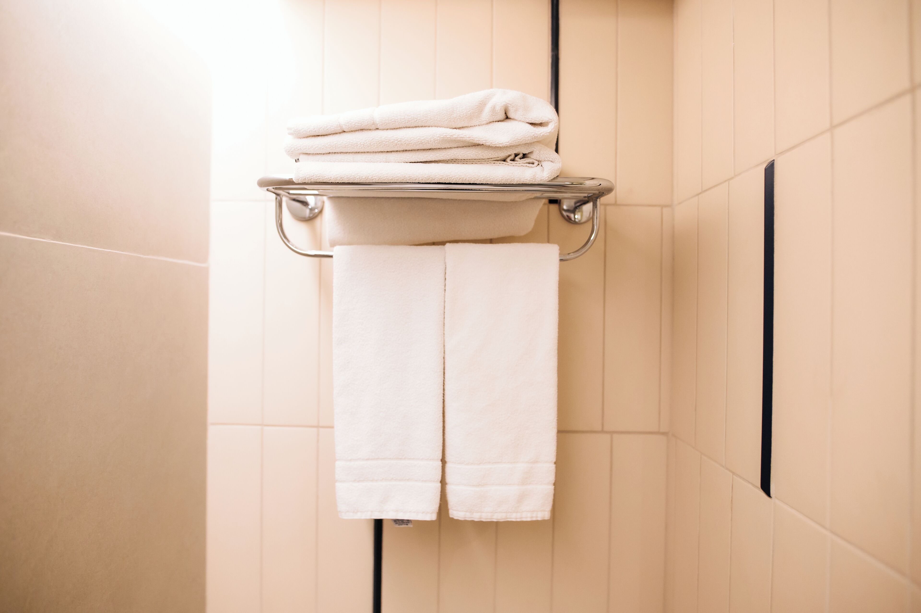 Un baño con un perchero que sostiene toallas dobladas y una toalla colgando.