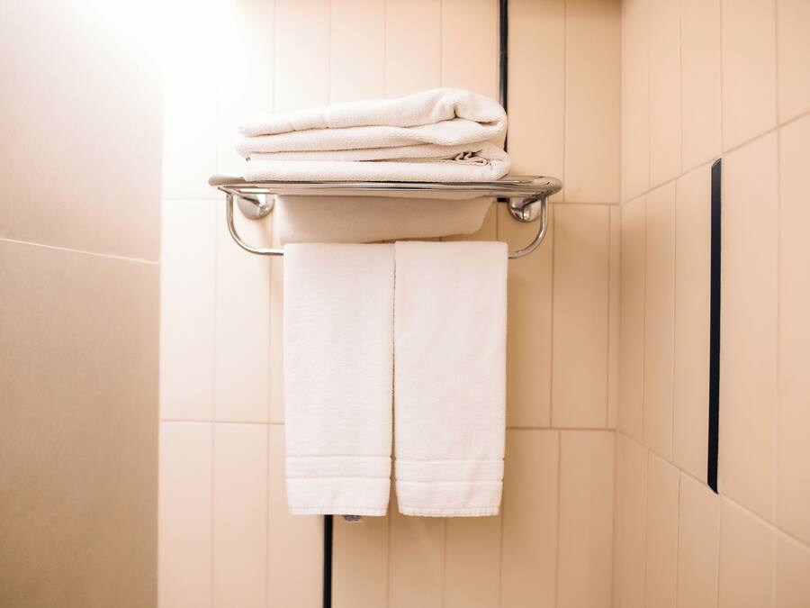 Un baño con un perchero que sostiene toallas dobladas y una toalla colgando.