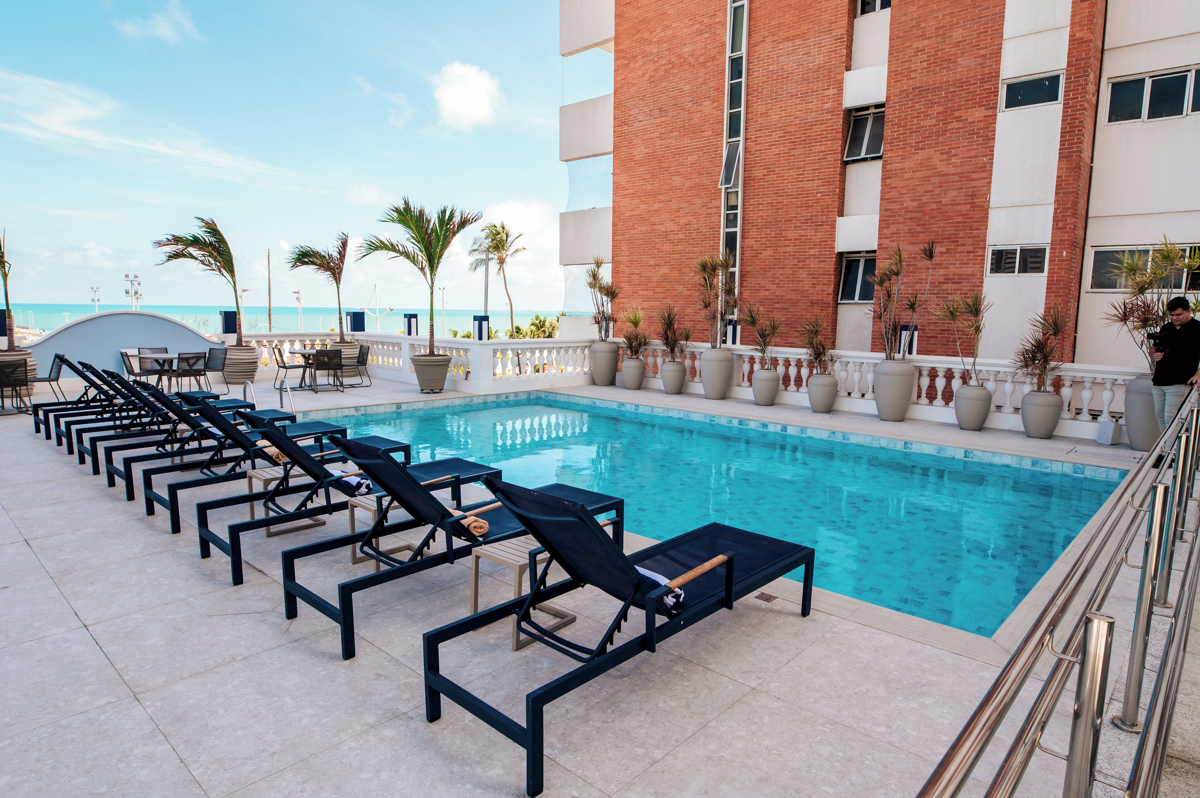 A poolside area with lounge chairs and a view of the ocean.