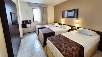 A hotel room with two beds, a desk, a TV, and a window with curtains.