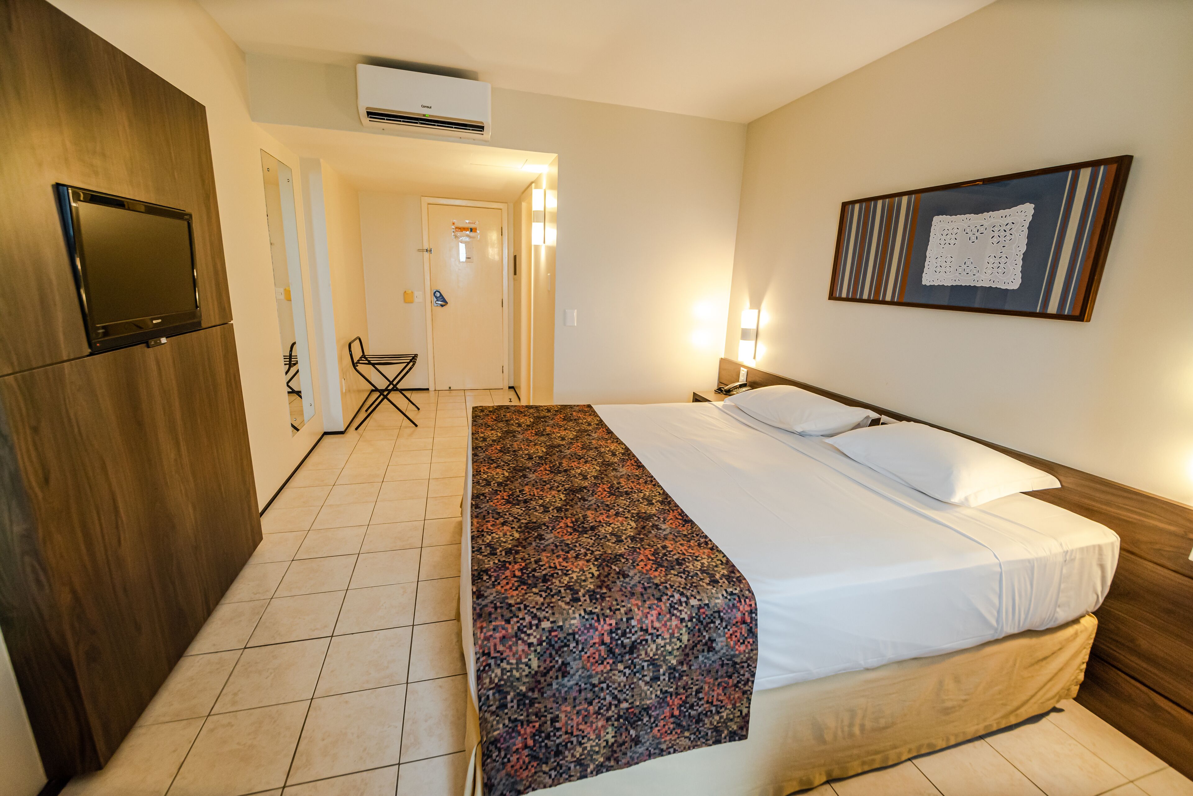 Habitación de hotel con cama, televisor, escritorio y una silla.