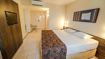 Habitación de hotel con cama, televisor, escritorio y una silla.