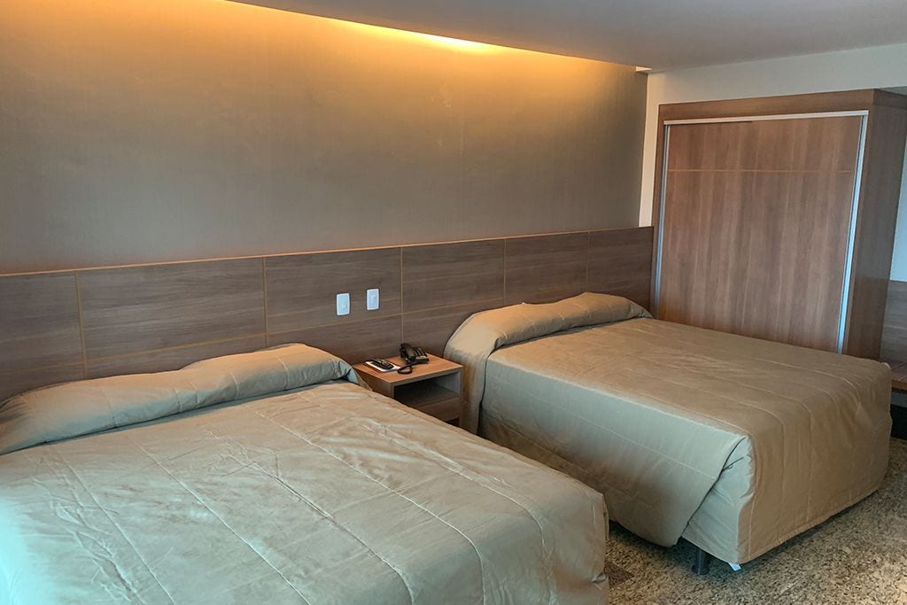 Ein Hotelzimmer mit zwei Betten, einem Nachttisch und einem Holzschrank.