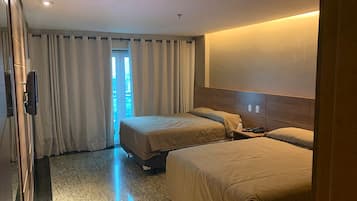 Ein Hotelzimmer mit zwei Betten, einem Holzkopfstück, einem Flachbildfernseher und Blick ins Freie durch ein Fenster.