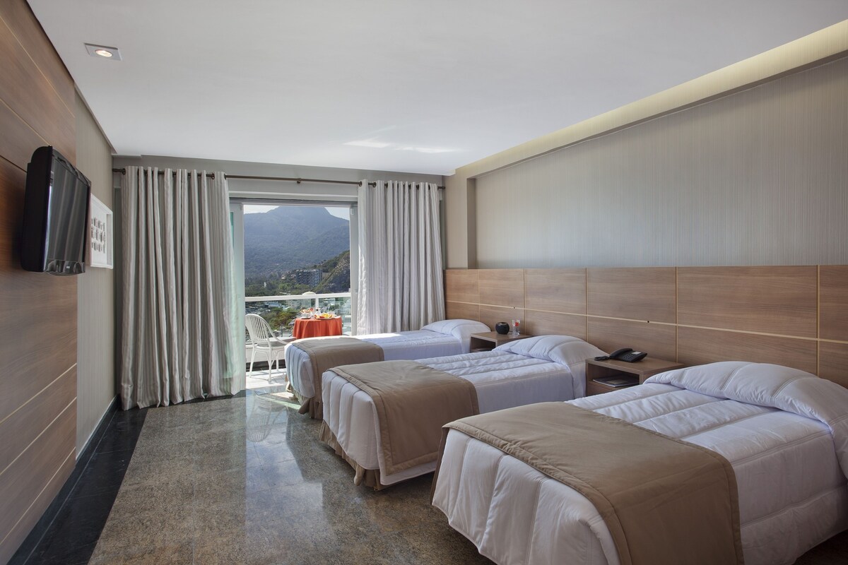 Ein Hotelzimmer mit zwei Betten, einem Flachbildfernseher, einem Tisch mit roter Tischdecke und Bergblick.