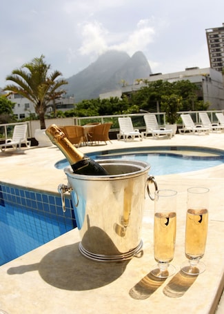 Una piscina al aire libre, sillones reclinables de piscina. Royalty Barra Hotel