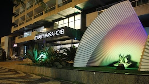 The exterior of the Royalty Barra Hotel with a modern design, including a unique curved facade and a well-lit entrance. - Royalty Barra Hotel (Rio de Janeiro)