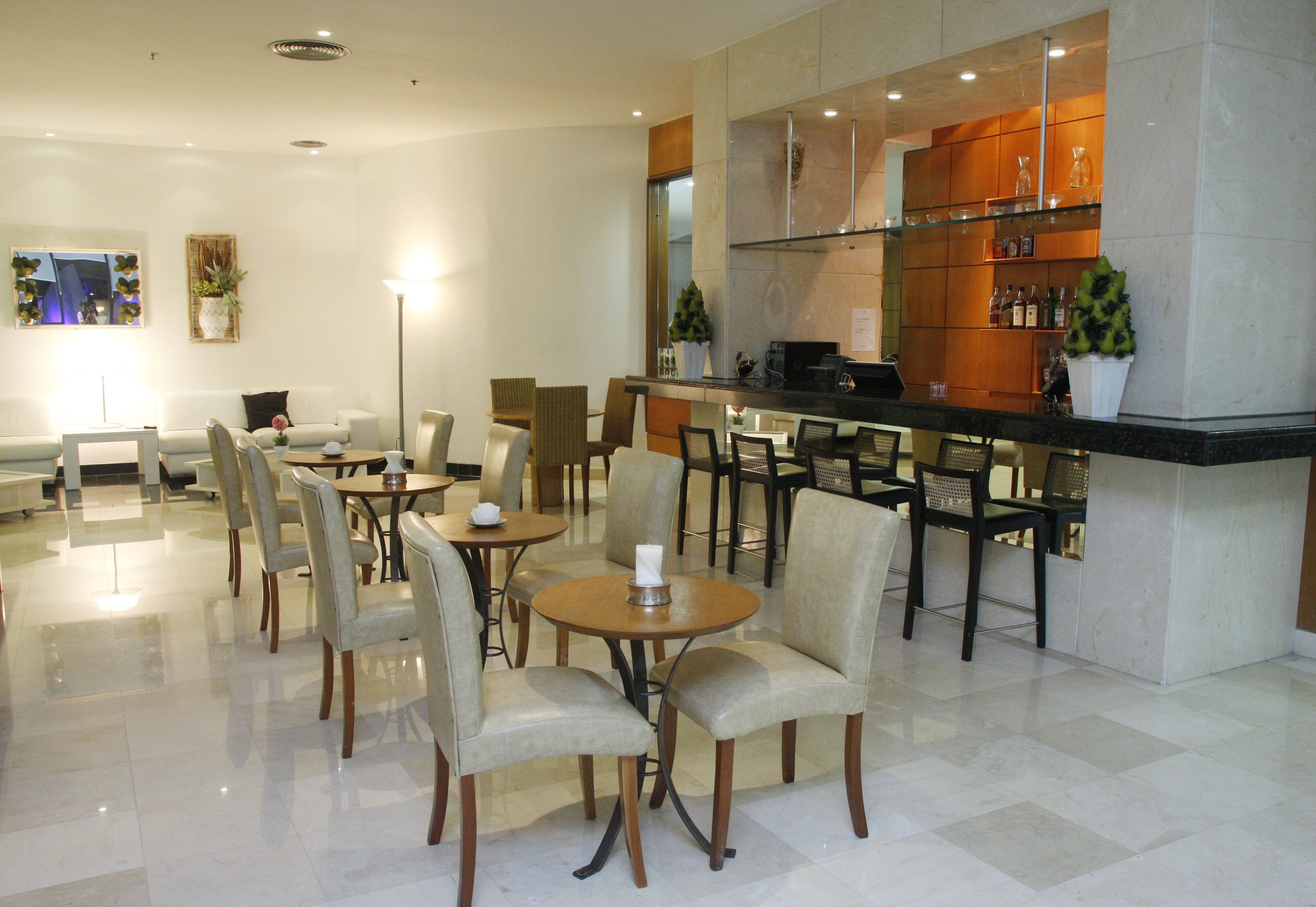 Un vestíbulo de hotel con varias zonas de estar, un mostrador de recepción y un bar.