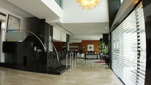 A modern lobby with a central staircase, a large chandelier, and a reception desk. - Royalty Barra Hotel (Rio de Janeiro)