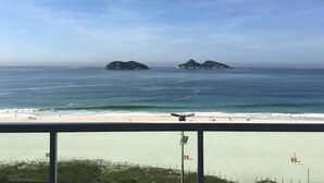 A beach with two small islands in the distance, a clear sky, and a sandy shore. - Royalty Barra Hotel (Rio de Janeiro)