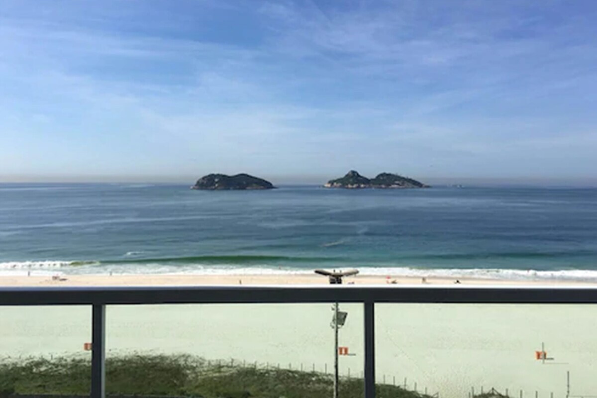 Ein Strand mit zwei kleinen Inseln in der Ferne, einem klaren Himmel und einem sandigen Ufer.