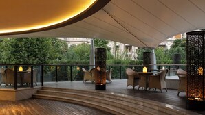 A modern outdoor seating area with tiered steps, lounge chairs, and decorative lighting.