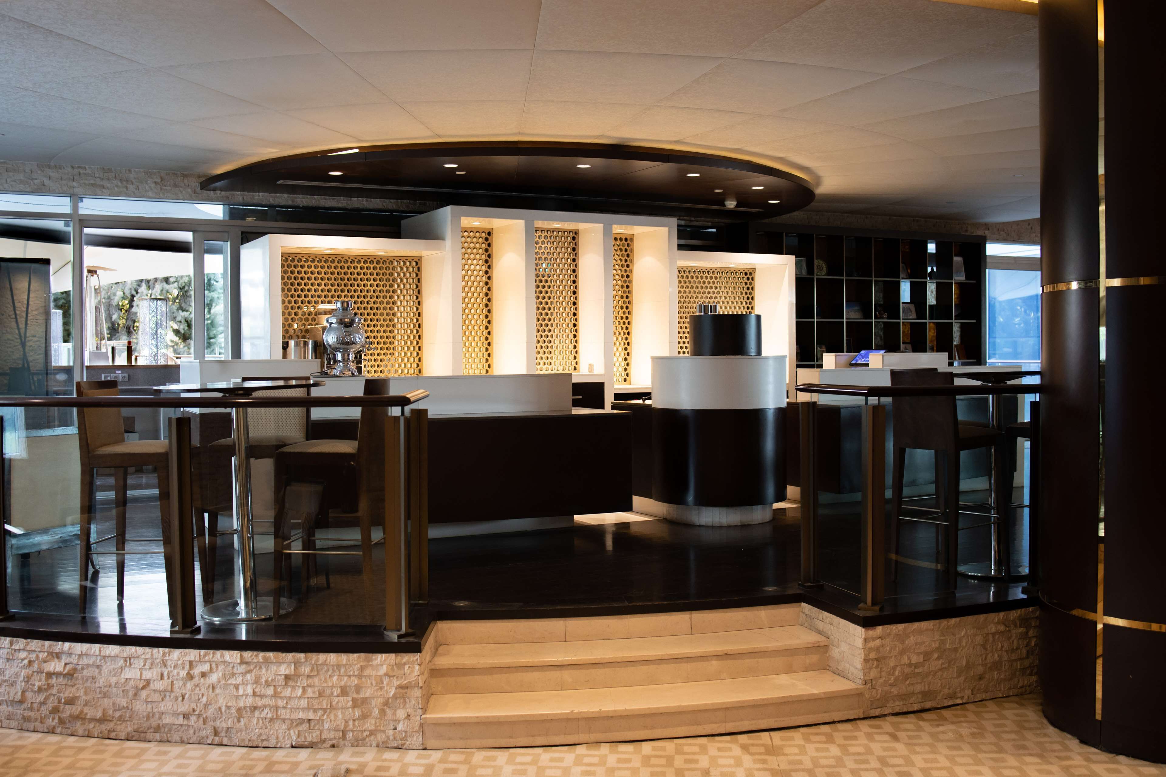 A modern lobby with a curved reception desk, glass railings, and a patterned floor.
