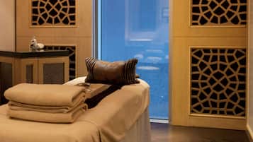 A hotel room with a bed, a small table with a vase, and decorative wooden panels.