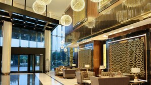 A modern lobby with a glass entrance, seating area, and decorative lighting.