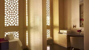 Enjoy a serene bathroom retreat with a large mirror, sink, and towel rack, set amidst decorative cut-out windows and a vase with fresh flowers.