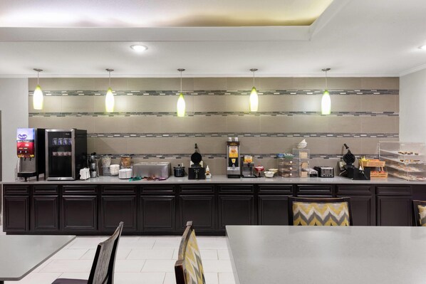 A modern kitchen with dark cabinets, a countertop with various appliances, and pendant lights.