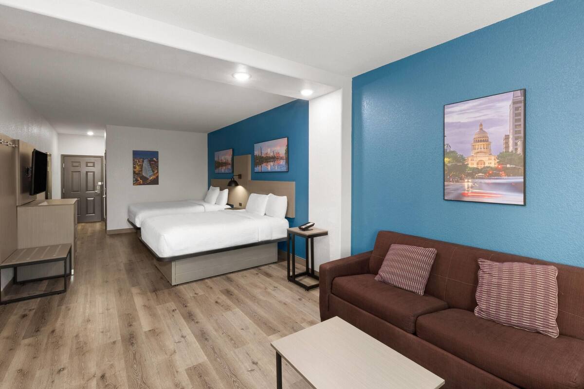 A hotel room with a bed, a sofa, a desk, and a TV.