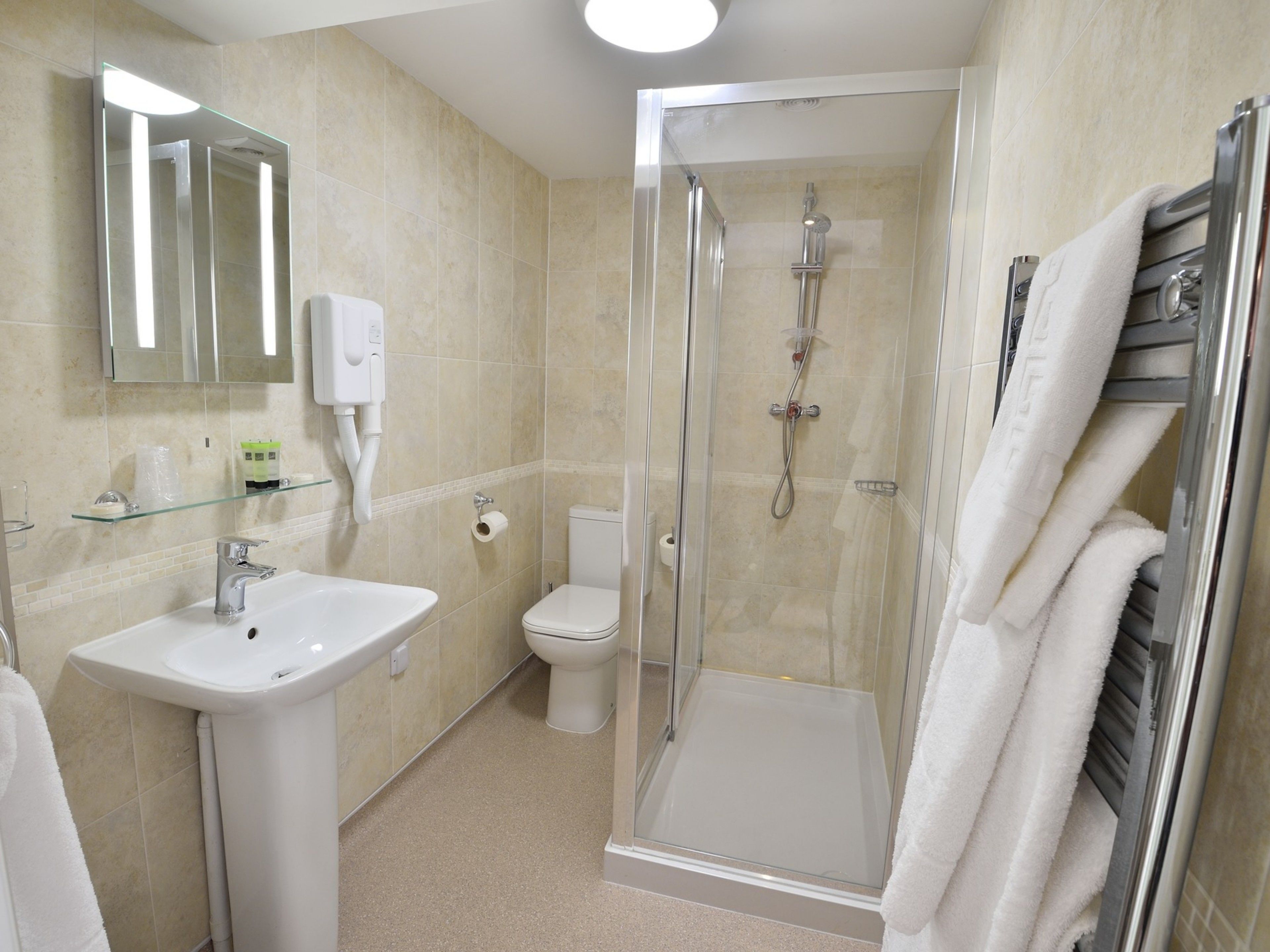 Ein modernes Badezimmer mit einer gläsernen Dusche, einem weißen Waschbecken und einer Toilette.